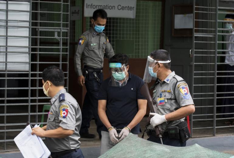 Canadian Christian pastor David Lah wears a mask and face shield as he is escorted by police at Mayangone Township Court in Yangon on May 20, 2020, as he faced charges over allegedly organizing religious gatherings despite a ban on mass events to halt the spread of the Covid-19 coronavirus. (STR / AFP)