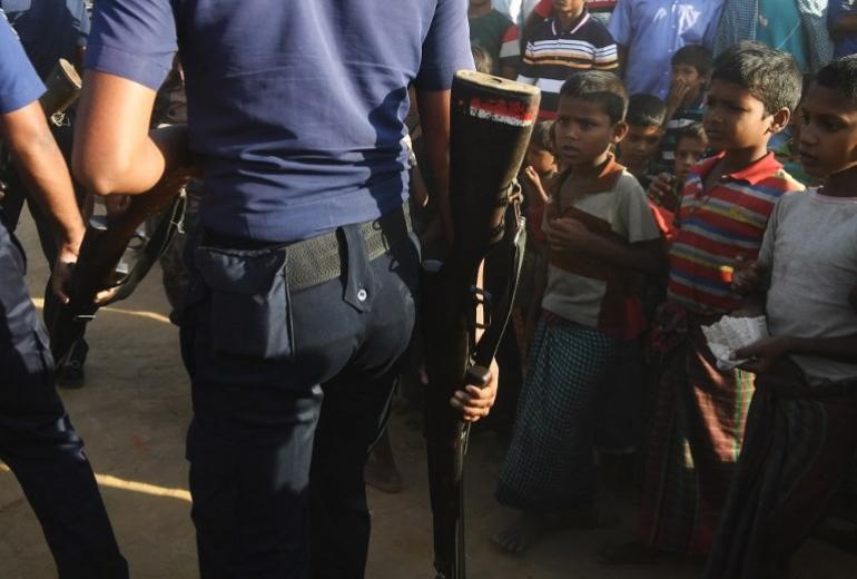  Rohingya refugees look on as Bangladeshi police officers walk past at the Unchiprang refugee camp near Teknaf. (Dibyangshu Sarkar / AFP)