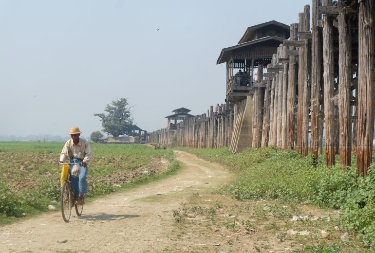 A man cycles along side tourist attraction U Bein Bridge near Amarapura. (Lorcan Lovett)