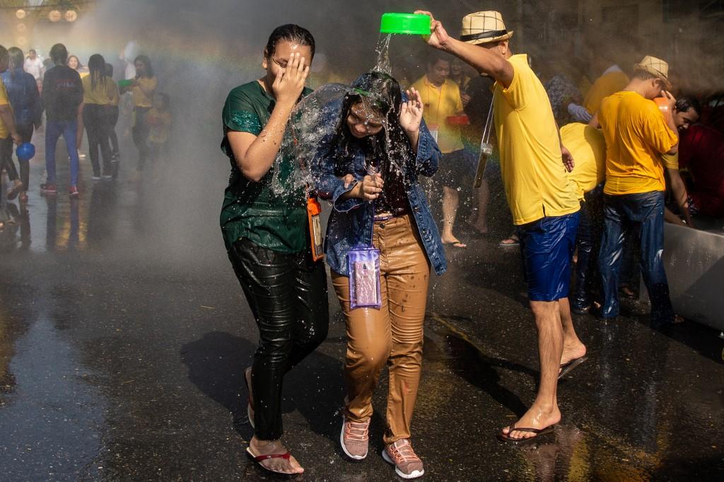 A reveller pours water on two women during celebrations for the Thingyan festival. (Sai Aung / AFP)