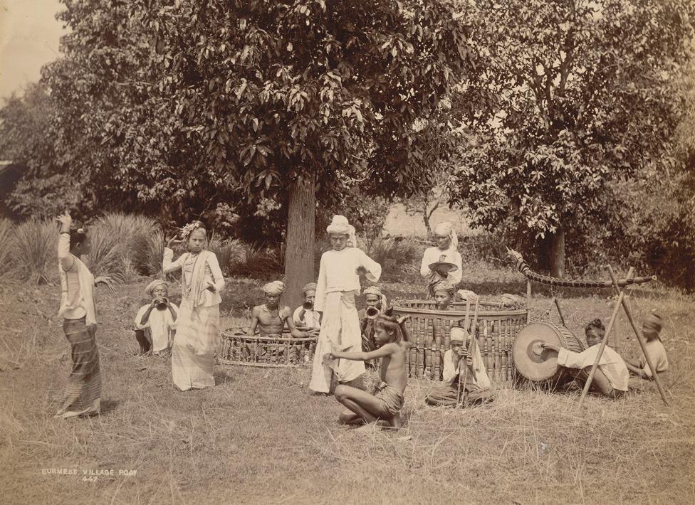 Photograph of a pwe or dance performance in Burma, taken by Philip Adolphe Klier in the 1890s. The circular frames in which two musicians sit are drum and gong instruments.