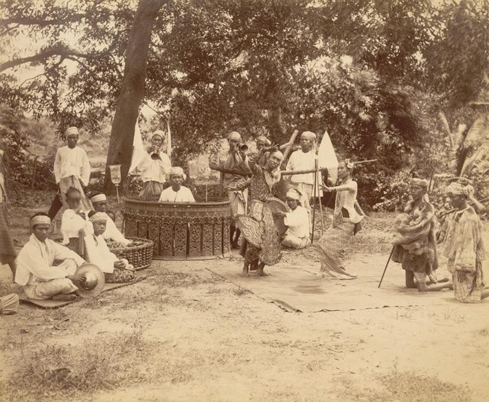 Photograph of a zat pwe in Burma (Myanmar), taken by Watts and Skeen in the 1890s. A zat pwe is the most popular of several different types of pwe, combining music, dance and drama into a play with a religious theme. This photograph shows a pair of dancers, who are supported by a band of musicians playing a variety of percussion and wind instruments which typically make up an outdoor ensemble or hsaing.