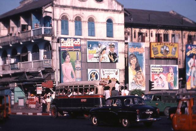 A Rangoon street scene. The middle poster portrays the wedding of Prince Charles and Lady Diana Spencer.