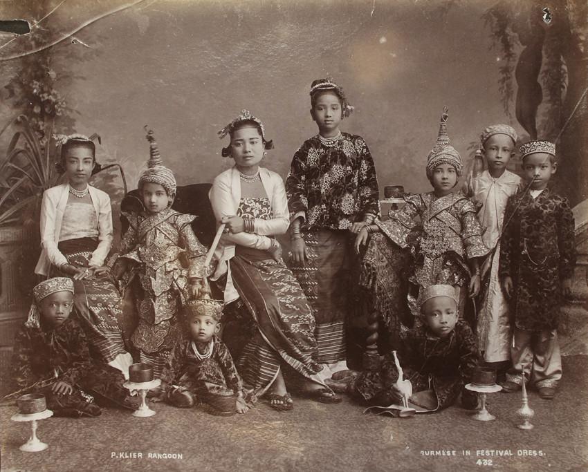 Burmese pose in festive dress for a studio portrait in Rangoon. (1907)