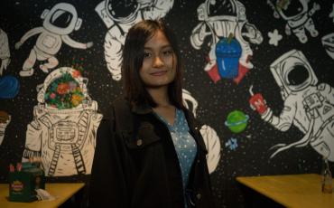 Thet Thet Soe, 19, poses in front of one of her wall paintings at Mario Juice and Snack Bar in Loikaw. (Yan Naing Aung)