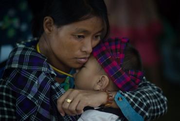 In this picture taken on May 13, 2018, an internally displaced woman and a child look on at a temporary shelter at a church compound in Myitkyina, Kachin state. (Ye Aung Thu / AFP)