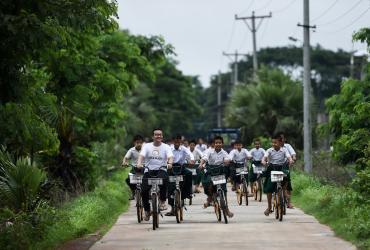 Mike Than Tun Win (second left) cycles with students on bicycles, previously used in bike-sharing companies and shipped from Singapore, which have been donated as part of the "Lesswalk" scheme on the outskirts of Yangon. (Ye Aung Thu / AFP)