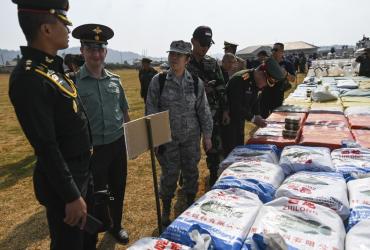 Foreign military attaches check drugs in a football ground where seized drugs, vehicles, laboratory accessories and precursor chemicals are being displayed to be witnessed by invited military attaches and journalists in Kawnghka at Shan state on March 6, 2020. (Ye Aung Thu / AFP)