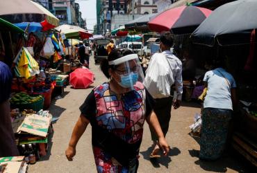  A woman, wears a face shield as a preventive measure against the spread of the COVID-19 novel coronavirus, walks through a street market in Yangon on April 21, 2020. (Sai Aung Main / AFP)