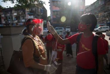 A National League for Democracy supporter checks the temperature for a fellow activist as they launch the campaign for the upcoming November 8 general election in Yangon on September 8, 2020. (Sai Aung Main / AFP)