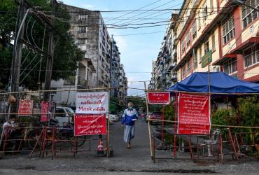  A man walks past a barrier blocking access to minor roads next to a sign recommending to residents to stay at home in Yangon on September 26, 2020, as new restrictions have been introduced to try to halt a surge in Covid-19 coronavirus cases. (Ye Aung Thu / AFP)