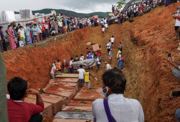 Volunteers bury bodies of miners in a mass grave as relatives look on during a funeral ceremony near Hpakant in Kachin state. (Zaw Moe Htet / AFP)