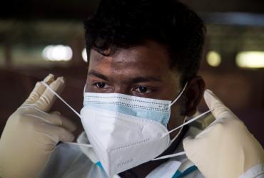 Volunteer Sithu Aung puts on a face mask as he prepares to bury a person suspected of dying from the Covid-19 coronavirus in Yangon. (Photos by Sai Aung Main / AFP)