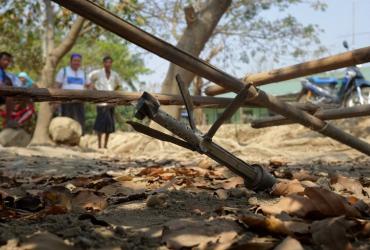 This photo taken on March 16, 2019 shows people looking at an unexploded rocket in the Mrauk U township in Rakhine. (STR / AFP)