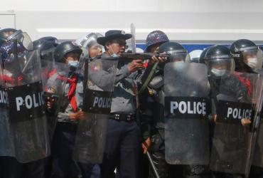 A police officer (centre) aims a gun during clashes with protesters taking part in a demonstration against the military coup in Naypyidaw, on Tuesday. (AFP)