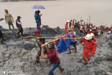 Rescuers carry the body of a jade miner pulled from the mud after a landslide in Kachin state. (Myanmar Fire Services Department / Facebook)