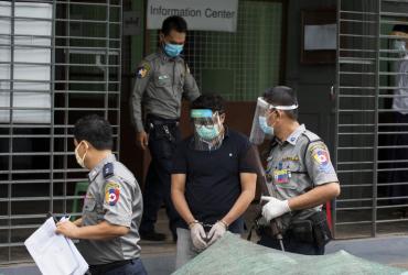 Canadian Christian pastor David Lah wears a mask and face shield as he is escorted by police at Mayangone Township Court in Yangon on May 20, 2020, as he faced charges over allegedly organizing religious gatherings despite a ban on mass events to halt the spread of the Covid-19 coronavirus. (STR / AFP)