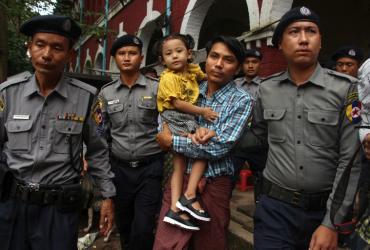Detained Myanmar journalist Kyaw Soe Oo carries his daughter while escorted by police to the Yangon courthouse on the first day of trial on July 16, 2018. (Myo Kyaw Soe / AFP)