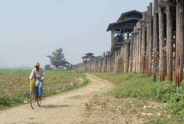 A man cycles along side tourist attraction U Bein Bridge near Amarapura. (Lorcan Lovett)