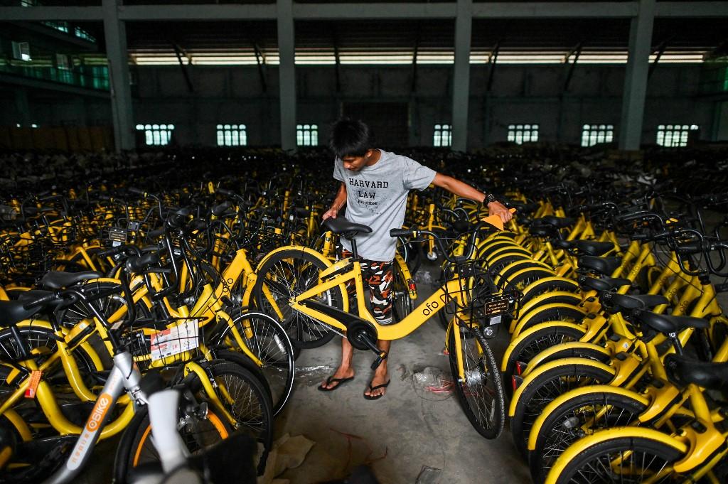  A man arranges bicycles previously used in bike-sharing companies, which were shipped from Singapore as part of the "Lesswalk" scheme, in a warehouse in Yangon. (Ye Aung Thu / AFP)