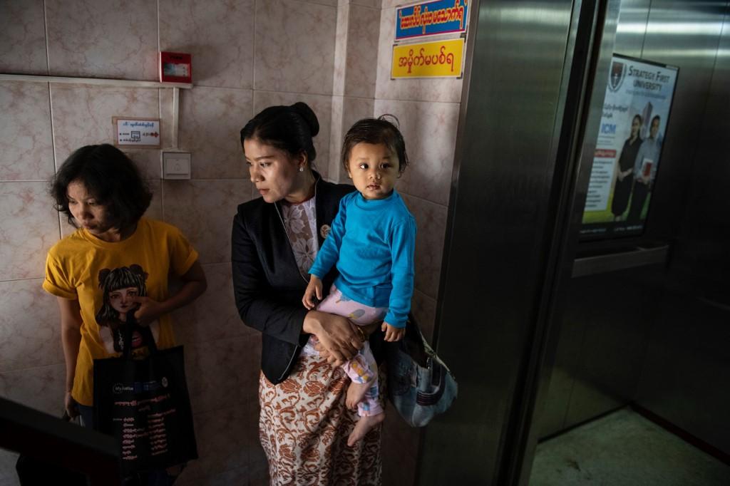 This photo taken on February 11, 2020 shows Legal Clinic Myanmar director Hla Hla Yee (C) carrying her daughter before a meeting at the Gender Equality Network office in Yangon. (Shwe Paw Mya Tin / AFP)