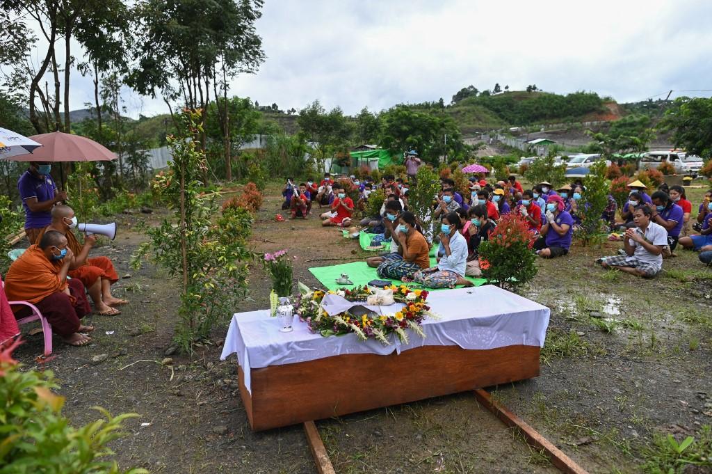 Htar Htar Myint (C) paying respect beside a coffin for her husband's funeral ceremony, following a deadly landslide in an area of open-cast jade mines, near Hpakant. (Ye Aung Thu / AFP)