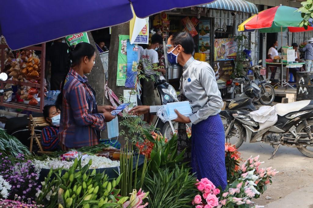 Myo Min Tun talks to a vendor as he campaigns in market in Mandalay, ahead of the November 8 general election. (Ye Naing Ye / AFP)