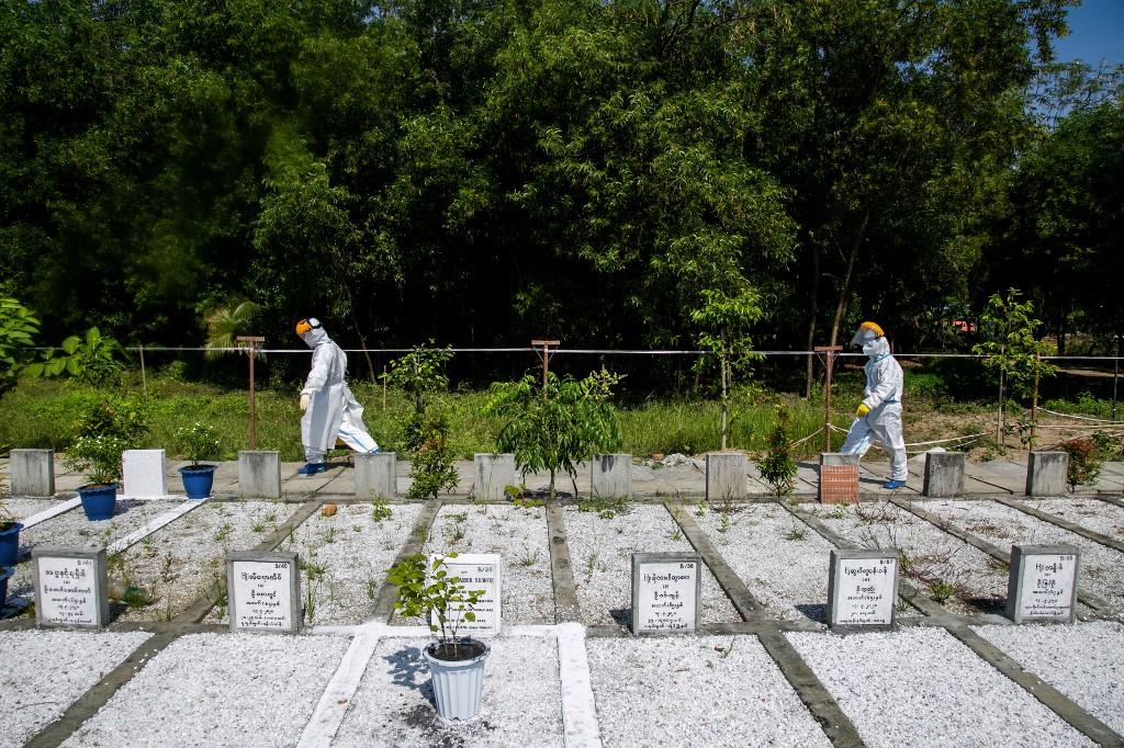 Volunteers wearing personal protective equipment (PPE) walk through the Hteinbin Muslim Cemetery after burying a person suspected of dying from the Covid-19 coronavirus in Yangon. 