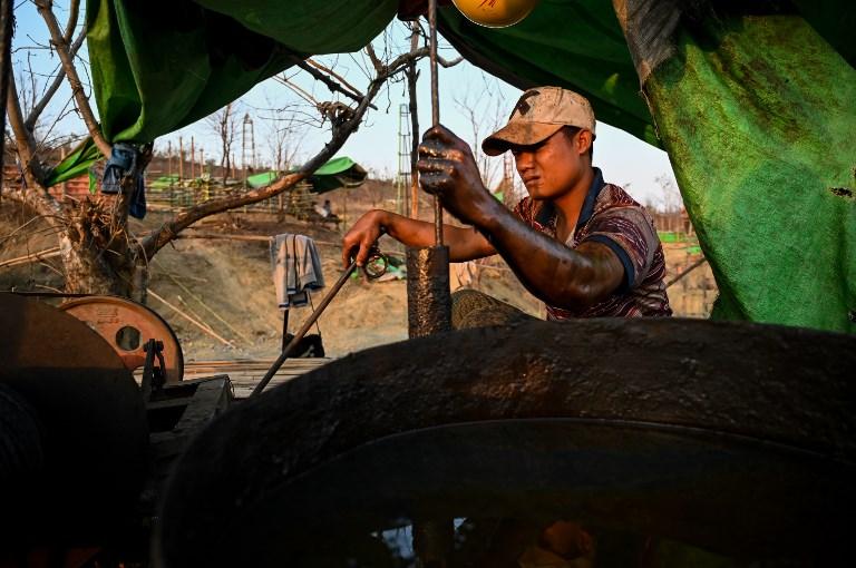  A worker operates a machine to extract crude oil from a well. (Ye Aung THU / AFP)