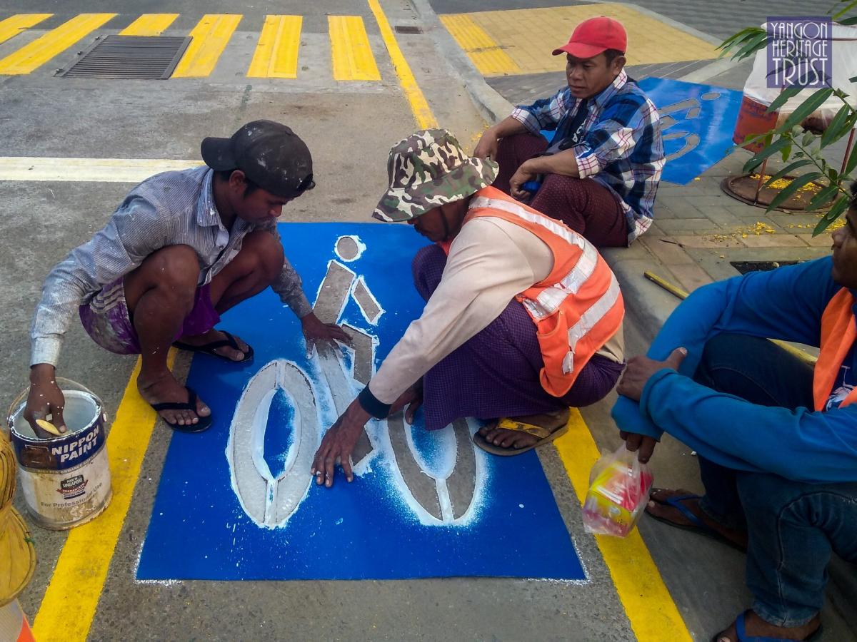 Workers paint a bicycle symbol on Seikkantha Street. (Yangon Heritage Trust)
