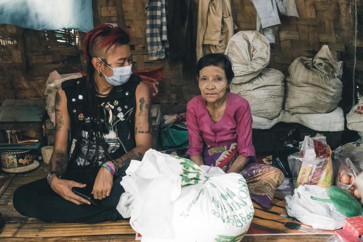 Kyaw Thu Win, a member of the Yangon chapter of Food Not Bombs, makes a food and cash donation to Daw Aye. (Kaung Kaung) 